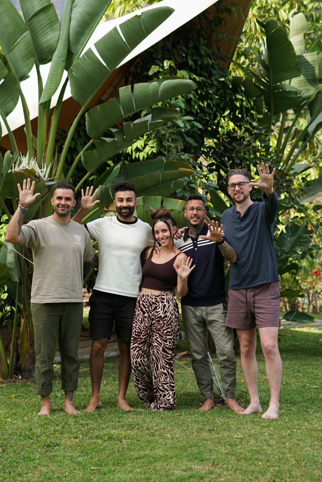 The Tandava Origins founding team standing together in a garden, waving